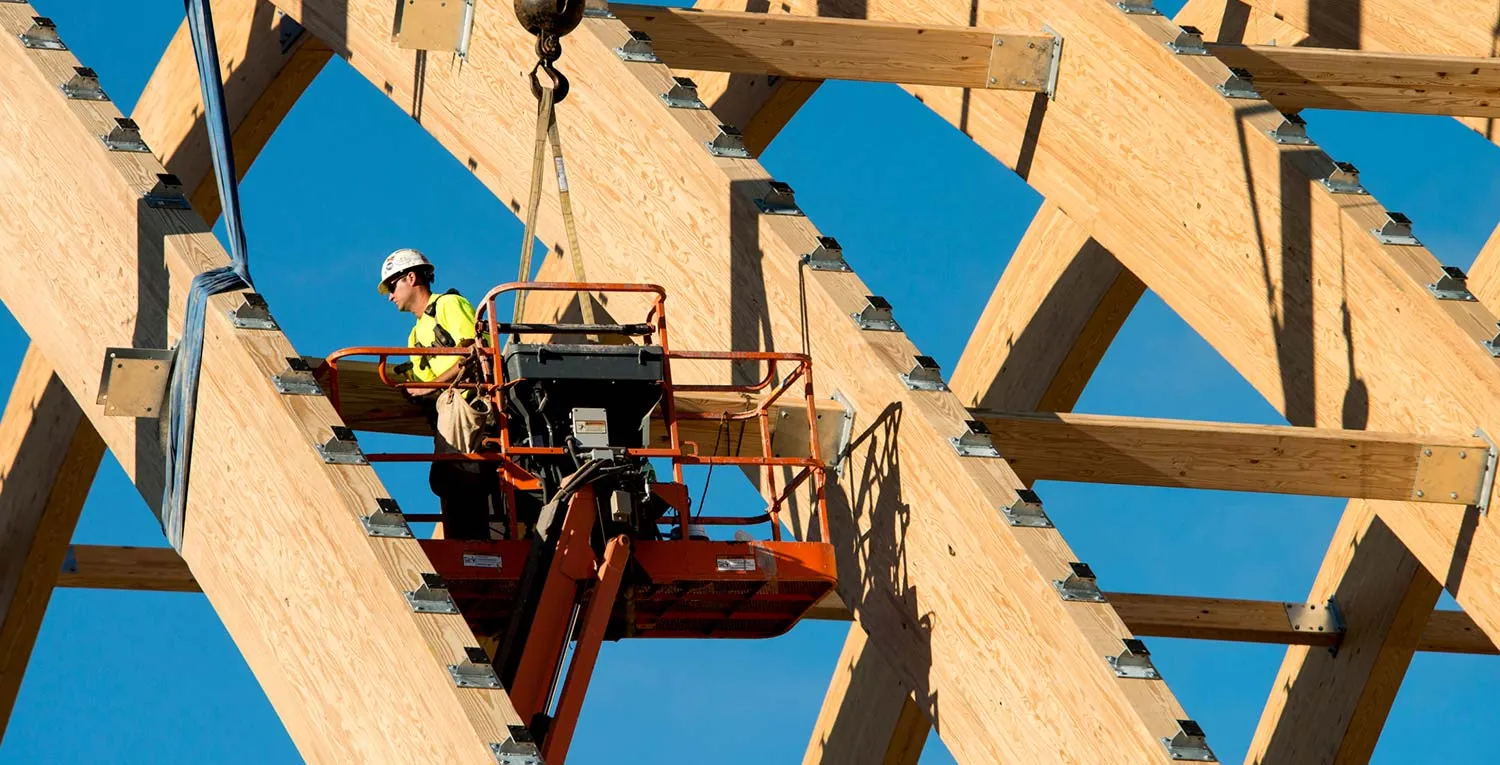 construction worker on lift working on wooden beams