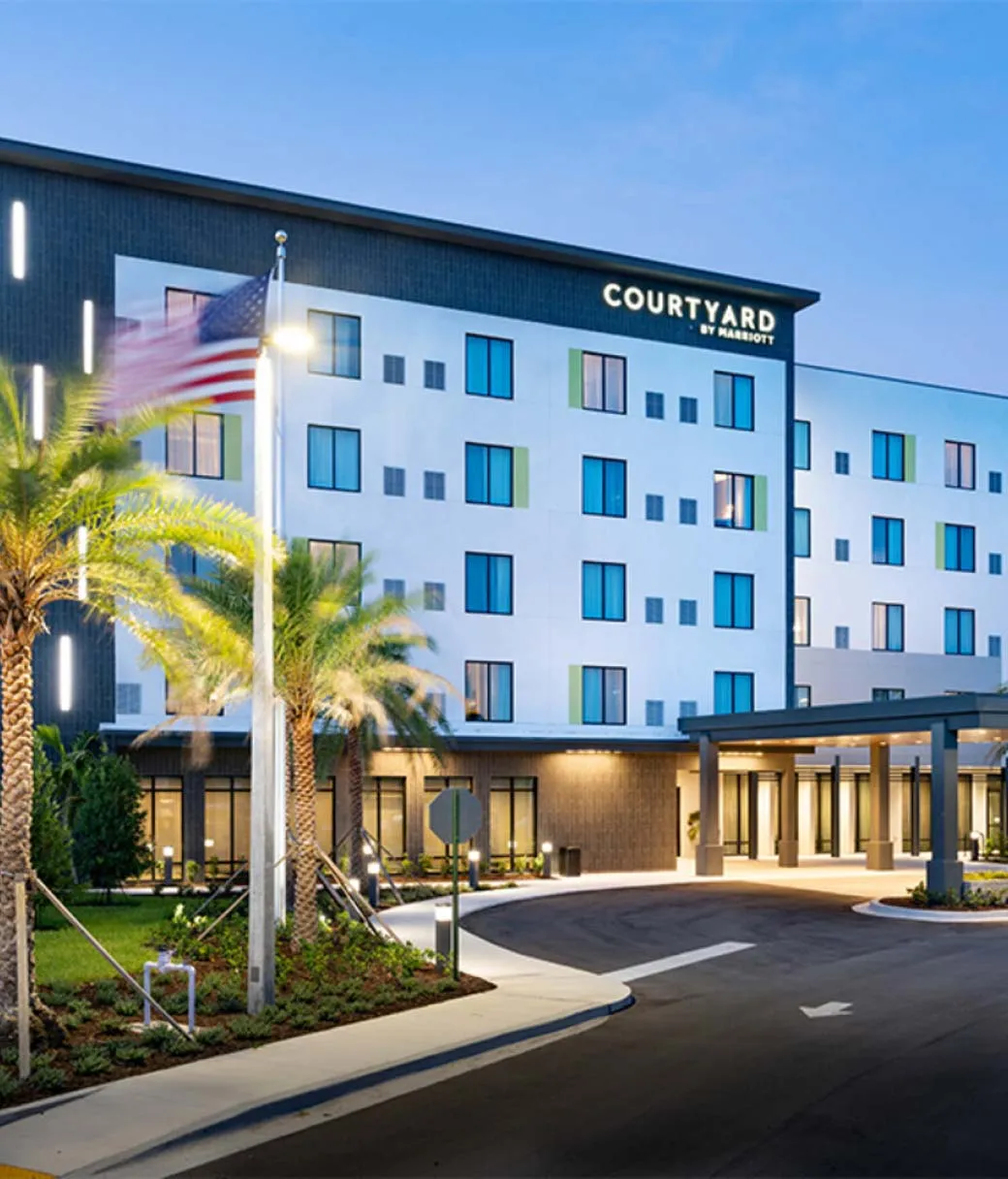 Courtyard by Marriot five story hotel with sidewalk and palm trees leading to entrance