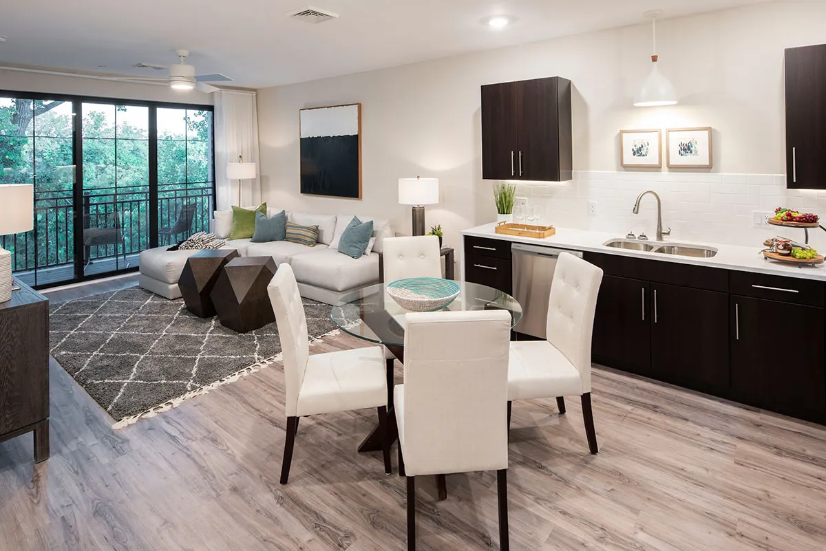 Apartment with kitchen with small table and chairs and living room with sliding glass doors