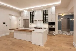 modern apartment kitchen with white cabinets and tall ceilings
