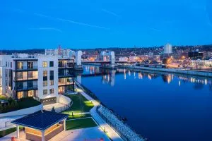 view of apartment building next to river with city of troy in background