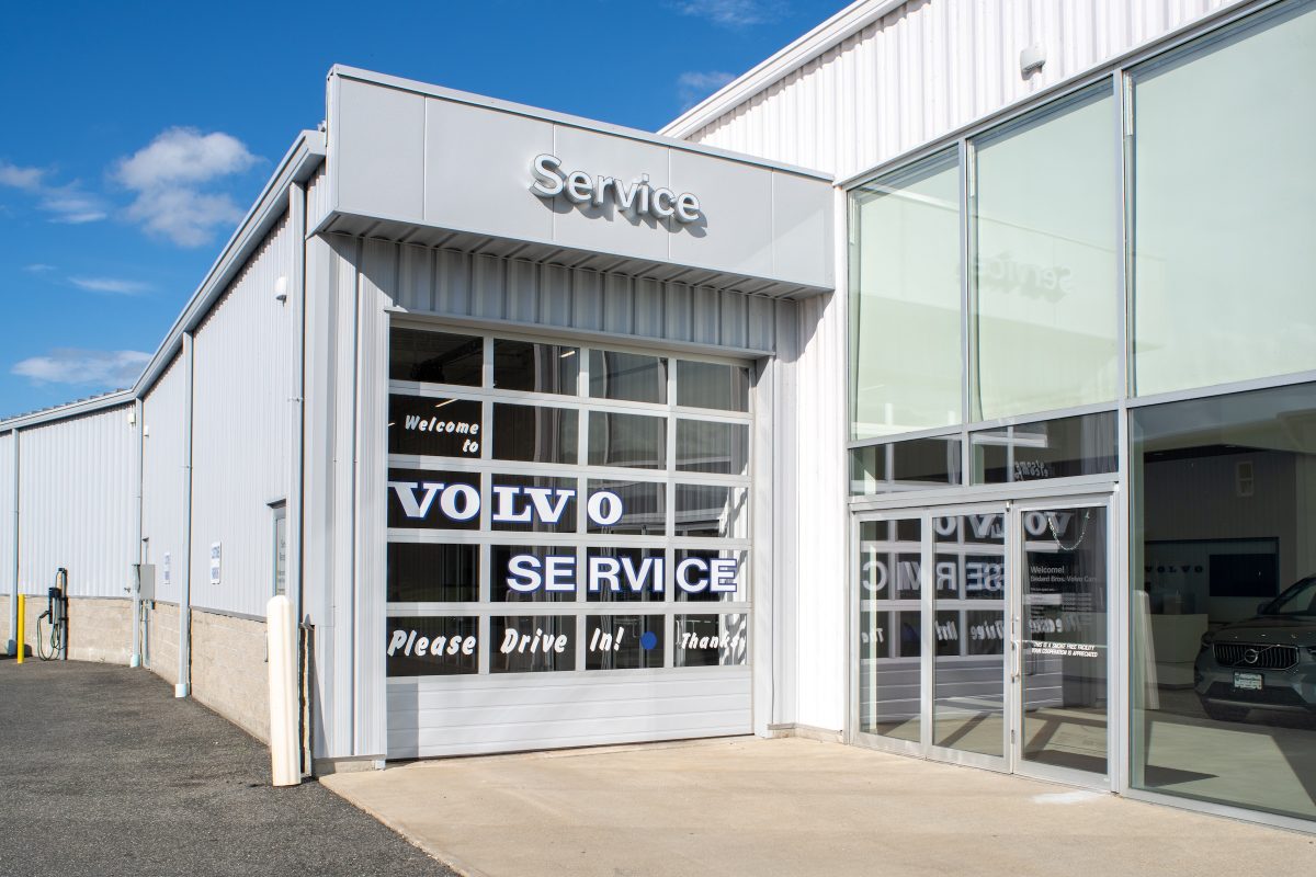 auto dealership service shop garage exterior with glass door and white siding